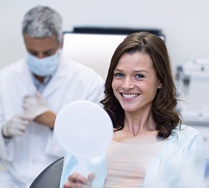woman in dental chair holding mirror