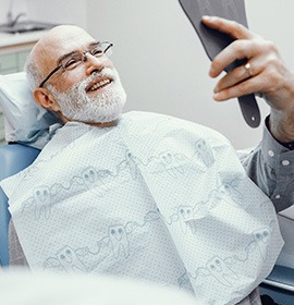 A bald, bearded man admiring his restored smile