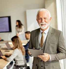 A senior businessman working on a digital tablet in an office