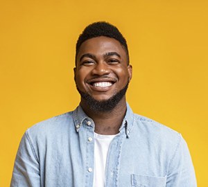 man smiling in front of yellow background