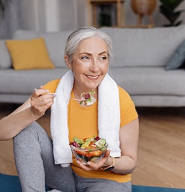 Older woman eating salad with dentures 