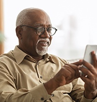 Senior man looking at phone on couch