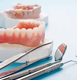 A full denture sitting next to dental tools