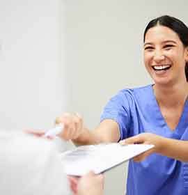 A nurse giving dental insurance forms to a patient