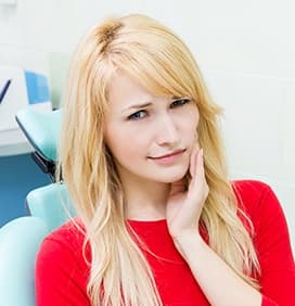 Woman in dental chair holding cheek