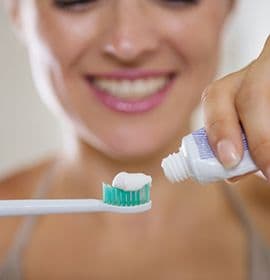 woman putting toothpaste on electric toothbrush