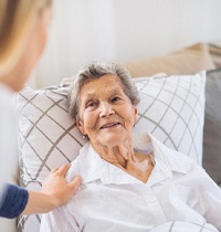Older woman with dental implants in Brampton resting in bed