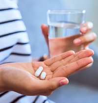 Woman holding medication and glass of water