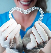 Dentist in white gloves holding Invisalign in the shape of a heart