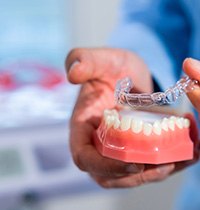 Dentist removing Invisalign from model lower arch