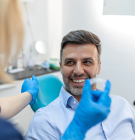 Patient smiling at dentist holding clear aligner