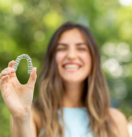 Closeup of smiling patient holding Invisalign aligner