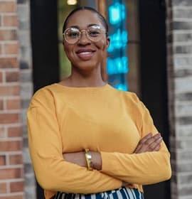 person smiling with their arms crossed