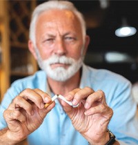 a man breaking a cigarette in half 