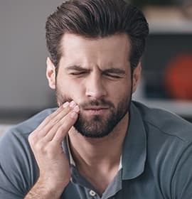 Man in pain holding cheek