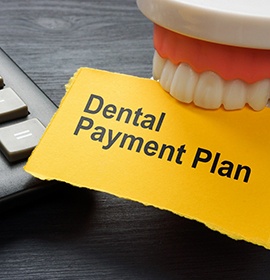Tooth model holding paper that says “dental payment plan”