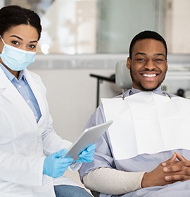 Male patient smiling in the treatment chair next to dentist