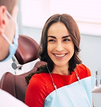 Woman in red shirt smiling at dentist during checkup