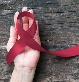 Hand holding oral cancer ribbon on wooden tabletop