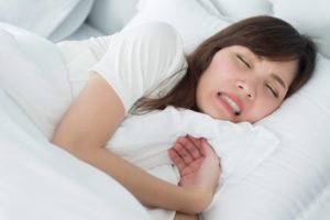 woman in bed grinding teeth while sleeping