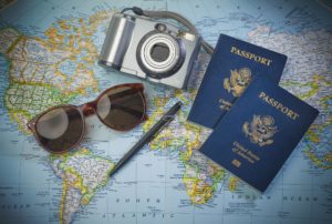 Passports, a camera, sunglasses, and a pen, on a map.