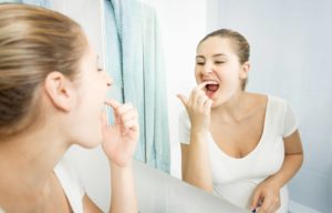 Woman checking teeth in mirror