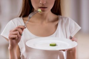 Woman hesitating to eat vegetable