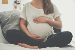 Pregant Woman sitting on Bed