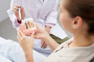 A closeup of a patient holding an enlarged dental implant model