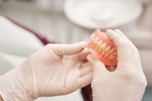 White-gloved hands holding full set of dentures