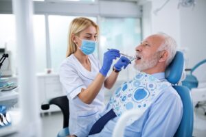 Older man being worked on by dental staff.